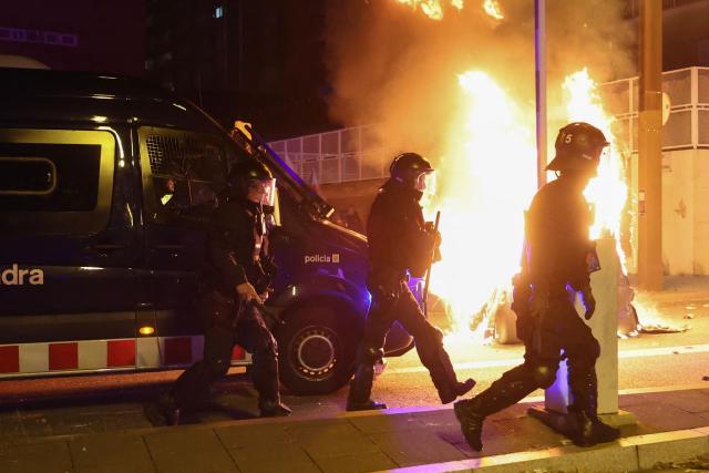 Police walk past a burning dumpster which was set alight during a demonstration in support of Palestinians, in Barcelona, on October 15, 2025. Despite the Gaza ceasefire deal signed on October 13, 2025 and a hostage and prisoner exchange between Israel and Hamas, demonstrations in support of the Palestinian people have continued to take place in several Spanish cities. (Photo by Josep LAGO / AFP)