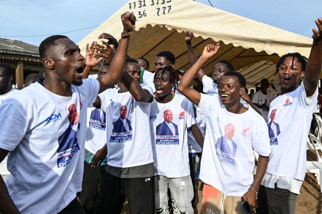Supporters wearing T-shirts bearing images of Ivorian independent presidential candidate Ahoua Don Mello cheer during his campaign rally at the commune of Port-Bouet in Abidjan on October 15, 2025. The west African nation will go to the polls on October 25 and incumbent Ouattara, in power since 2011, is vying for a fourth term in office. (Photo by Sia KAMBOU / AFP)
