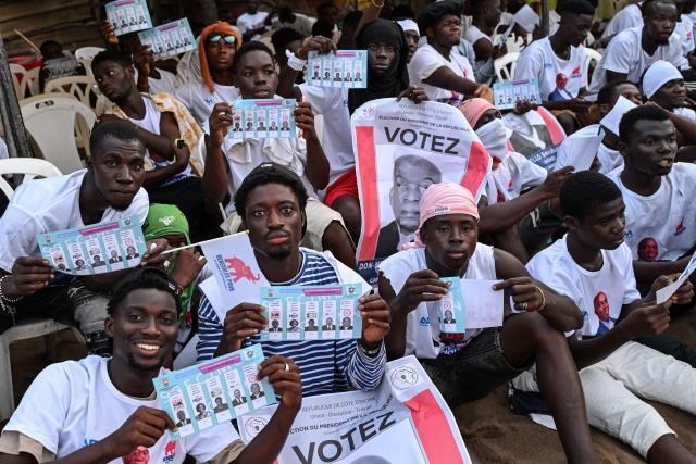 Supporters wearing T-shirts bearing images of Ivorian independent presidential candidate Ahoua Don Mello hold electoral leaflets during his campaign rally at the commune of Port-Bouet in Abidjan on October 15, 2025. The west African nation will go to the polls on October 25 and incumbent Ouattara, in power since 2011, is vying for a fourth term in office. (Photo by Sia KAMBOU / AFP)
