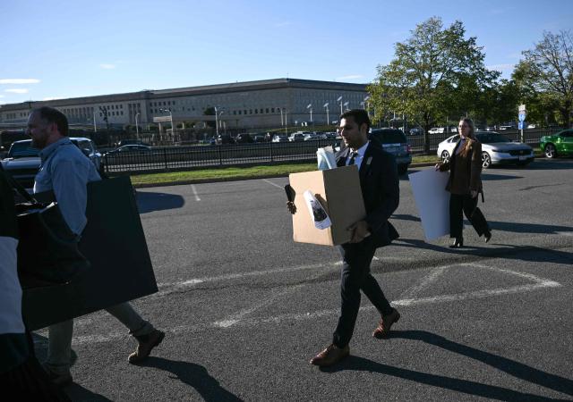 Reporters carry their belongings from the Pentagon in Washington, DC, on October 15, 2025 after US and international news outlets including The New York Times, AP, AFP and Fox News declined to sign new restrictive Pentagon media rules, and were stripped of their press access credentials. The new rules come after the Defense Department restricted media access inside the Pentagon, forced some outlets to vacate offices in the building and drastically reduced the number of briefings for journalists. (Photo by Brendan SMIALOWSKI / AFP)