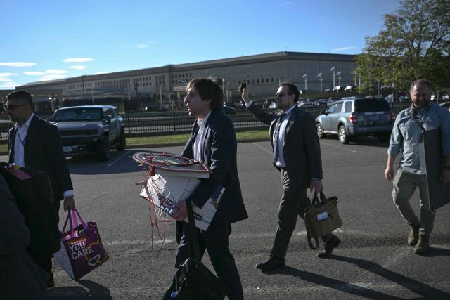 Reporters carry their belongings from the Pentagon in Washington, DC, on October 15, 2025 after US and international news outlets including The New York Times, AP, AFP and Fox News declined to sign new restrictive Pentagon media rules, and were stripped of their press access credentials. The new rules come after the Defense Department restricted media access inside the Pentagon, forced some outlets to vacate offices in the building and drastically reduced the number of briefings for journalists. (Photo by Brendan SMIALOWSKI / AFP)
