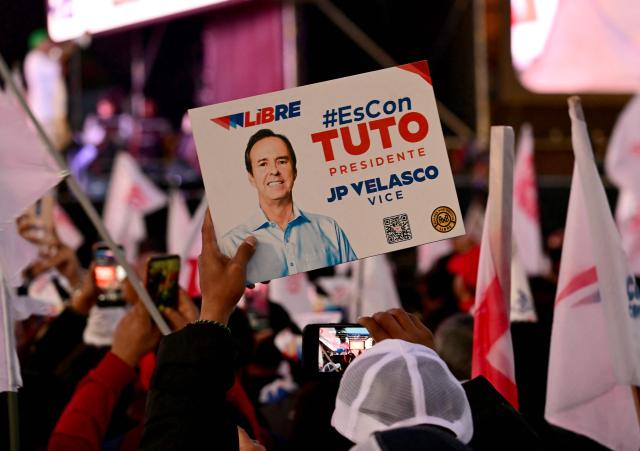 A supporter of Bolivia's presidential candidate for the Freedom and Democracy (Libre) Alliance, Jorge "Tuto" Quiroga, holds a banner with his picture during his closing campaign rally in La Paz on October 15, 2025. An ex-president and a senator will go head-to-head in Bolivia's presidential runoff on October 19, 2025, both with promises to fix the South American country's broken economy. Senator Rodrigo Paz came from behind to take the top spot with 32 percent of votes cast in a first round in August, but has since fallen behind ex-president Jorge "Tuto" Quiroga in stated voter intention. (Photo by MARTIN BERNETTI / AFP)