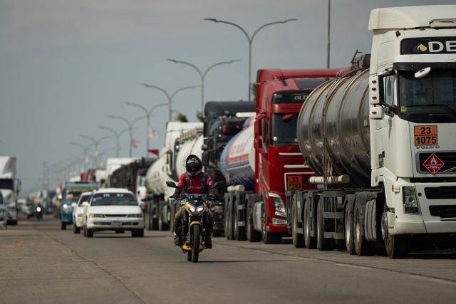 A man rides past fuel tankers near a refinery in Santa Cruz, Bolivia on October 15, 2025. Bolivia will choose a president from among two right-wing candidates Sunday after two decades of socialist rule, with voters hoping for urgent measures to address foreign currency, fuel and food shortages. (Photo by ERNESTO BENAVIDES / AFP)
