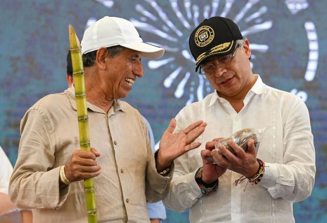 Colombia's President Gustavo Petro (R) chats with FARC dissidence commander Walter Mendoza during a ceremony to destroy war material in Puerto Asis, Colombia on October 15, 2025. Petro said on october 15, 2025, he would boycott an upcoming US-supported Summit of the Americas, deepening a rift with Washington -- which has already stripped him of a US visa. (Photo by David SALAZAR / AFP)