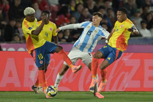 Argentina's midfielder #15 Tomas Perez fights for the ball with Colombia's forward #10 Oscar Perea and midfielder #19 Kener Gonzalez during the 2025 FIFA U-20 World Cup semi-final football match between Argentina and Colombia at the National Stadium in Santiago on October 15, 2025. (Photo by Rodrigo ARANGUA / AFP)