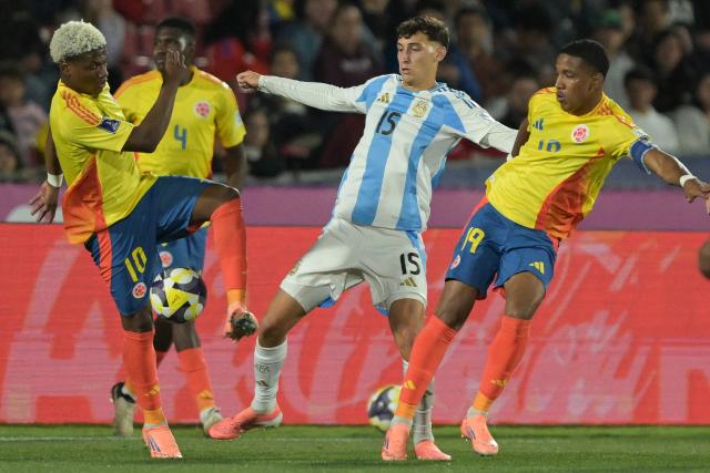 Argentina's midfielder #15 Tomas Perez fights for the ball with Colombia's forward #10 Oscar Perea and midfielder #19 Kener Gonzalez during the 2025 FIFA U-20 World Cup semi-final football match between Argentina and Colombia at the National Stadium in Santiago on October 15, 2025. (Photo by Rodrigo ARANGUA / AFP)