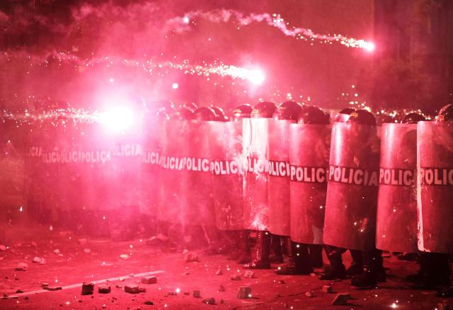 Anti-riot police officers take cover from fireworks as they clash with demonstrators during a protest against Peru's interim President Jose Jeri in Lima on October 15, 2025.  (Photo by CONNIE FRANCE / AFP)
