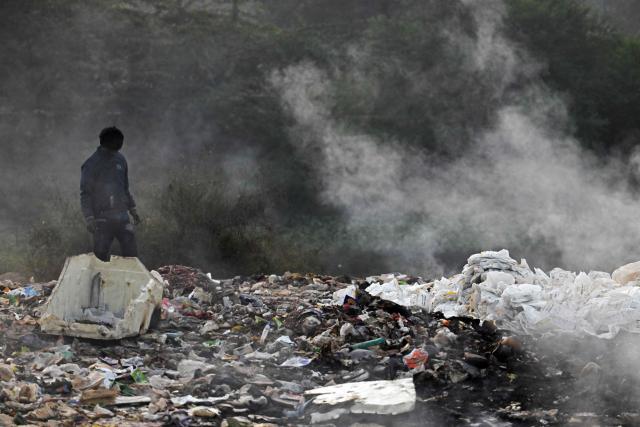 (FILES) A boy looks for reusable waste as smoke billows from burning garbage at the Ghazipur landfill amid smoggy conditions in New Delhi on November 19, 2024. Pollution levels in India's capital city Delhi is shaping decisions on parenthood -- forcing a small yet growing number of people to flee because of the health hazards associated with toxic air. Home to more than 30 million people, New Delhi and the surrounding metropolitan area consistently tops world rankings for air pollution. (Photo by Arun SANKAR / AFP)