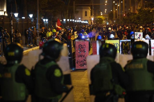 Anti-riot police officers take cover from demonstrators during a protest against Peru's interim President Jose Jeri in Lima on October 15, 2025.  (Photo by Hugo CUROTTO / AFP)