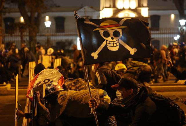 Demonstrators holding a flag of the manga series "One Piece" clash with anti-riot police officers during protest against Peru's interim President Jose Jeri in Lima on October 15, 2025.  (Photo by Hugo CUROTTO / AFP)