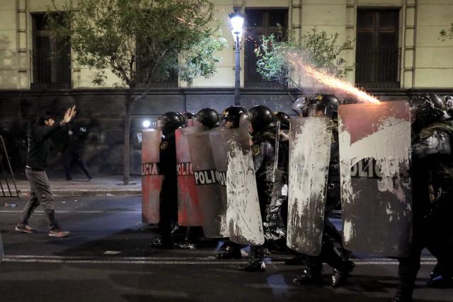 A demonstrator gestures in front of riot police during a protest against Peru's interim President Jose Jeri in Lima on October 15, 2025. Violence at a rally in Peru's capital on Wednesday left at least 55 police officers and 20 civilians injured, President Jose Jeri, who assumed the top role less than a week ago, said. (Photo by Connie FRANCE / AFP)