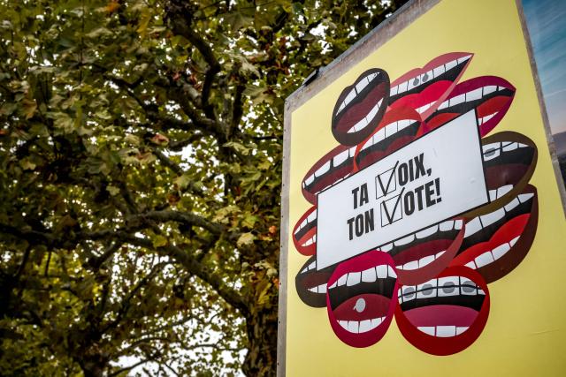 An electoral poster which reads as 'Your voice, your vote' and encouraging citizens to vote is displayed in Geneva on October 15, 2025. No other country in the world holds as many popular initiatives as Switzerland. The first votes were held more than a century ago. Swiss citizens regularly go to the polls to decide on local, regional, and national issues. (Photo by Fabrice COFFRINI / AFP)