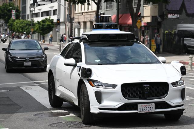 (FILES) A Waymo autonomous self-driving Jaguar electric vehicle drives in downtown Los Angeles, California on May 1, 2025. US food delivery app DoorDash announced October 15, 2025 that Waymo driverless cars will soon shuttle orders to some customers in a budding partnership with the Google-owned robotaxi star. The alliance will start in coming months with Waymo cars delivering take-away meals, groceries and convenience shop items to DoorDash users in the southwestern US city of Phoenix, according to the companies. (Photo by Patrick T. Fallon / AFP)