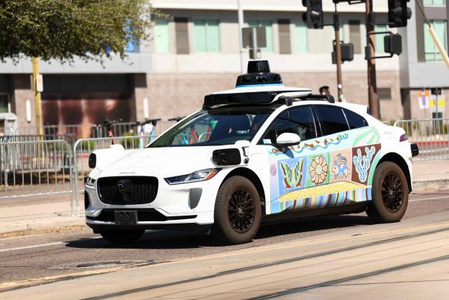 (FILES) A Waymo autonomous self-driving Jaguar electric vehicle is seen in Tempe, Arizona, on the outskirts of Phoenix, on September 15, 2025. US food delivery app DoorDash announced October 15, 2025 that Waymo driverless cars will soon shuttle orders to some customers in a budding partnership with the Google-owned robotaxi star. The alliance will start in coming months with Waymo cars delivering take-away meals, groceries and convenience shop items to DoorDash users in the southwestern US city of Phoenix, according to the companies. (Photo by CHARLY TRIBALLEAU / AFP)