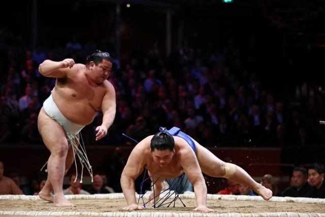 Hitoshi (L) throws Oshoumi (R) to the ground to win their bout during the Grand Sumo Tournament at the Royal Albert Hall in central London on October 16, 2025. (Photo by HENRY NICHOLLS / AFP)