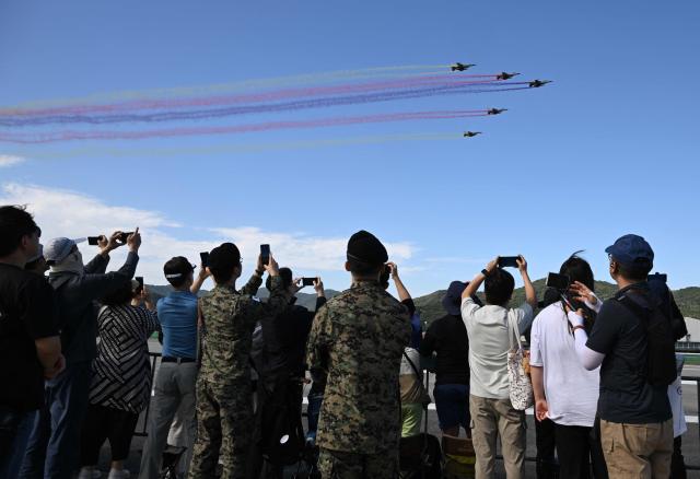 Visitors watch from the tarmac as KF-16 fighter jets fly in formation during the Seoul International Aerospace and Defence Exhibition (ADEX) at a military airport in Seongnam on October 17, 2025. (Photo by Jung Yeon-je / AFP)