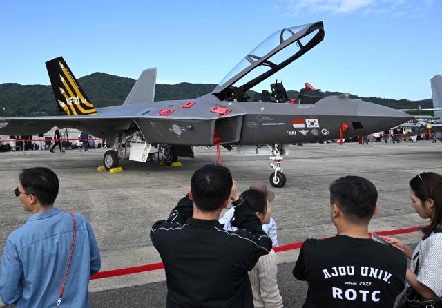 Visitors look at a KF-21 fighter jet during the Seoul International Aerospace and Defence Exhibition (ADEX) at a military airport in Seongnam on October 17, 2025. (Photo by Jung Yeon-je / AFP)