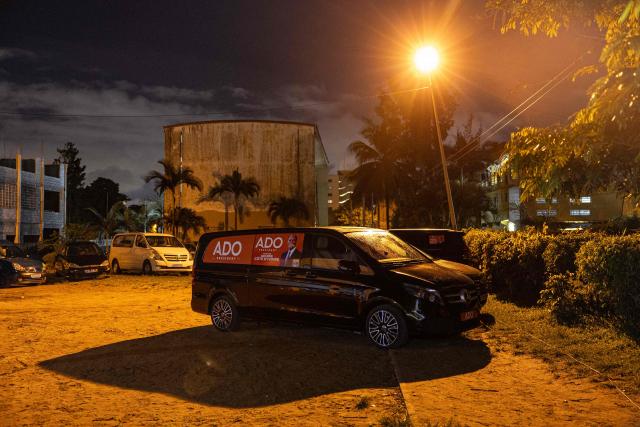 A general view of a minivan with window stickers depicting Ivorian President and presidential candidate for Rally of Houphouetists for Democracy and Peace (RHDP) Alassane Ouattara is parked during a political gathering ahead of the upcoming presidential election in Cocody near Abidjan on October 16, 2025. (Photo by EMMANUEL CROSET / AFP)