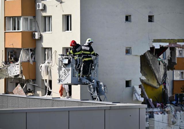 Members of the fire brigade inspect the roof of a school opposite a block of flats were partially destroyed by an explosion in Bucharest, Romania on October 17, 2025. Three people have died and 13 were hospitalized in Romania’s capital Bucharest following a strong explosion on October 17, 2025, according to rescue services. (Photo by Daniel MIHAILESCU / AFP)