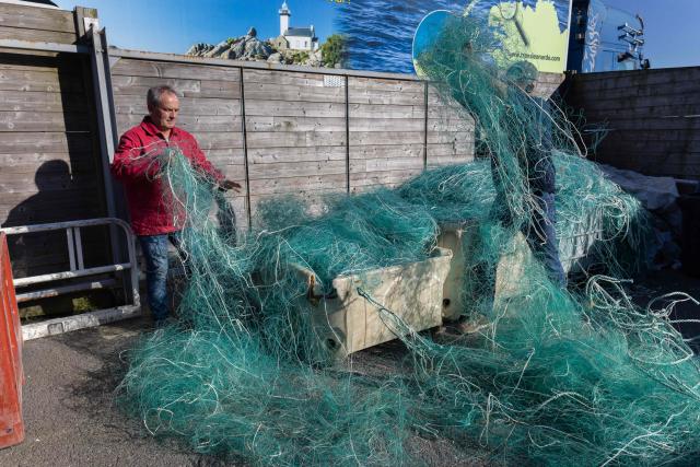 French charity association "Kernic Solidarites" member in charge of logistic Christian Abaziou (R) and its president Gerard Le Duff (L) sort out fishnets collected by the association to be send to Ukraine and use as protections against drone attacks, in the Britany port of Roscoff, on October 17, 2025. (Photo by Fred TANNEAU / AFP)