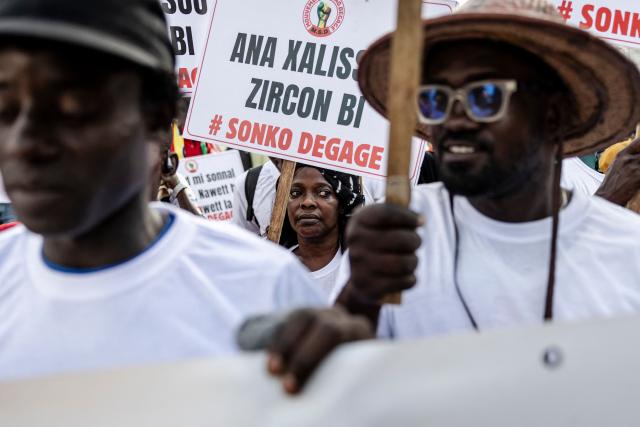 A protester holds a placard reading "Sonko get out" during a demonstration against high cost of living and the government in Dakar on October 17, 2025. (Photo by PATRICK MEINHARDT / AFP)