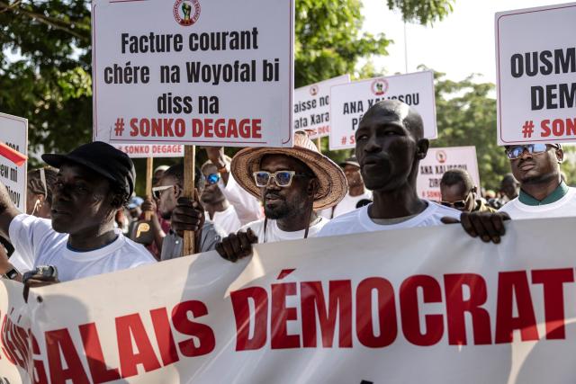 Protesters carry placards and chant slogans as they march during a demonstration against high cost of living and the government in Dakar on October 17, 2025. (Photo by PATRICK MEINHARDT / AFP)
