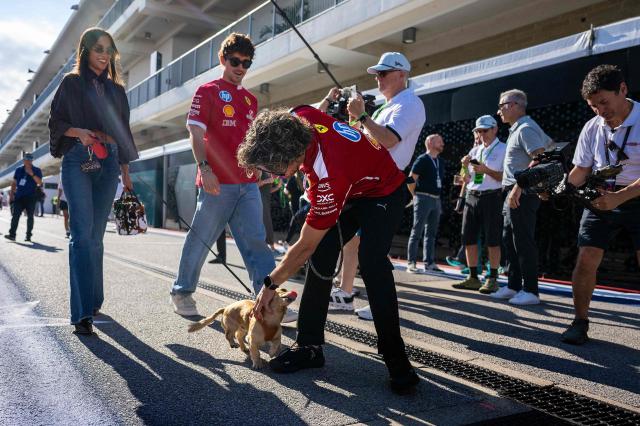 Ferrari's Monegasque driver Charles Leclerc and his girlfriend Alexandra Saint Mleux walk with their dog Leo as they arrive in the paddock ahead of the practice session for the United States Formula One Grand Prix at the Circuit of the Americas in Austin, Texas, on October 17, 2025. (Photo by Jim WATSON / AFP)