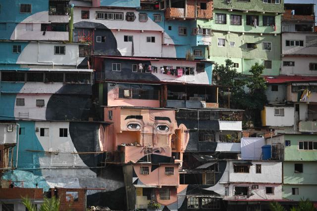 A giant mural of Venezuelan doctor Josй Gregorio Hernбndez, also known as "the doctor of the poor", is seen painted across the facades of several houses in the El Saman de Bolнvar community, in the Petare neighborhood of Caracas, on October 17, 2025. Pope Leo XIV is set to canonize Venezuela’s first saints, Dr. Jose Gregorio Hernandez and Sister Maria del Carmen Rendiles, during a ceremony in St. Peter's Square on October 19, 2025. (Photo by Federico PARRA / AFP)