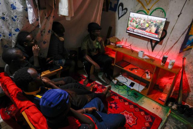 People watch the live broadcast of the public mourning in Kibera, Nairobi, on October 18, 2025 of Kenya’s opposition leader and former Prime Minister Raila Odinga taking place in Kisumu. Vast crowds gathered in Kisumu on October 18, 2025 to see the body of a beloved politician, Raila Odinga, for the biggest day of mourning ceremonies that have already claimed at least five lives. (Photo by SIMON MAINA / AFP)