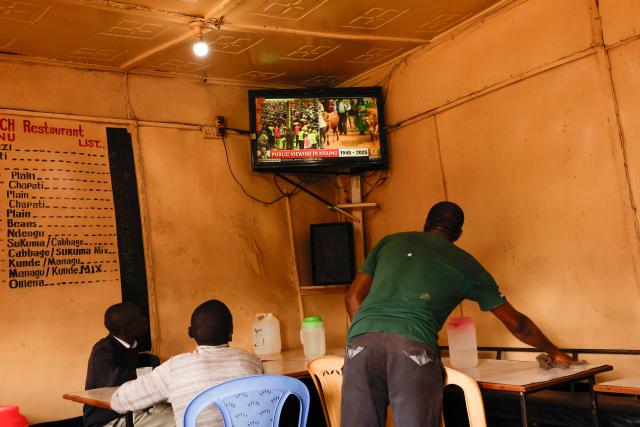 People watch the live broadcast of the public mourning ceremony in Kibera, Nairobi, on October 18, 2025 of Kenya’s opposition leader and former Prime Minister Raila Odinga taking place in Kisumu. Vast crowds gathered in Kisumu on October 18, 2025 to see the body of a beloved politician, Raila Odinga, for the biggest day of mourning ceremonies that have already claimed at least five lives. (Photo by SIMON MAINA / AFP)