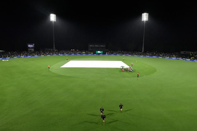 A general view shows the covers on the pitch as rain delays the first Twenty20 international cricket match between New Zealand and England at Hagley Oval in Christchurch on October 18, 2025. (Photo by Sanka Vidanagama / AFP)