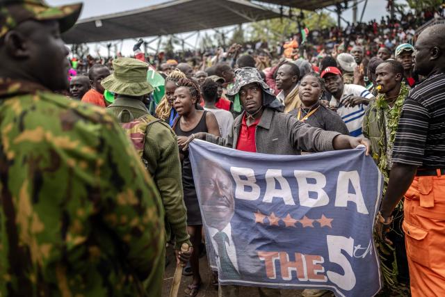 A supporter of Kenya’s opposition leader and former Prime Minister Raila Odinga holds a banner as mourners line up to view his coffin upon the arrival of his funeral proceedings to his home region in Kisumu, on October 18, 2025. Vast crowds gathered in western Kenya on October 18, 2025 to see the body of a beloved politician, Raila Odinga, for the biggest day of mourning ceremonies. (Photo by Luis TATO / AFP)