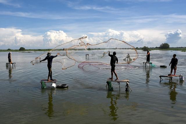 Cambodian men throw their fishing nets into a lake in Kandal province, near Phnom Penh, on October 18, 2025. (Photo by TANG CHHIN Sothy / AFP)