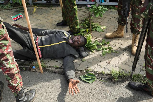 Kenyan police surround a distraught mourner who breached the barricade after a military helicopter bearing the remains of Kenya’s opposition leader and former Prime Minister Raila Odinga as it arrived at the Jomo Kenyatta Stadium in Kisumu on October 18, 2025. Vast crowds gathered in western Kenya on October 18, 2025 to see the body of a beloved politician, Raila Odinga, for the biggest day of mourning ceremonies. (Photo by Tony KARUMBA / AFP)