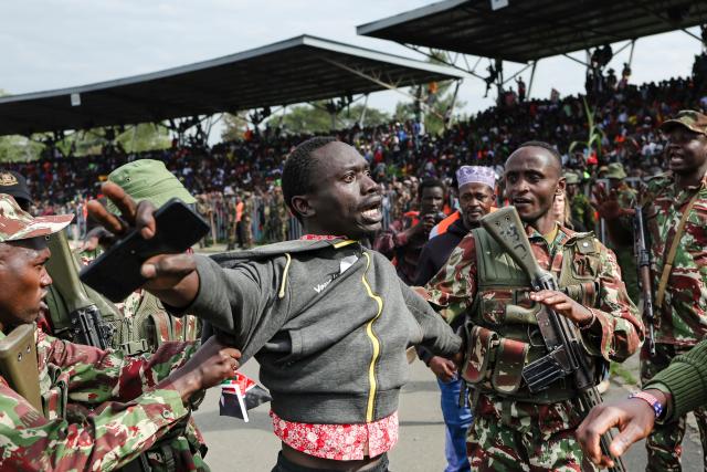 Kenyan police detain a distraught mourner who breached the barricade after a military helicopter bearing the remains of Kenya’s opposition leader and former Prime Minister Raila Odinga as it arrived at the Jomo Kenyatta Stadium in Kisumu on October 18, 2025. Vast crowds gathered in western Kenya on October 18, 2025 to see the body of a beloved politician, Raila Odinga, for the biggest day of mourning ceremonies. (Photo by Tony KARUMBA / AFP)