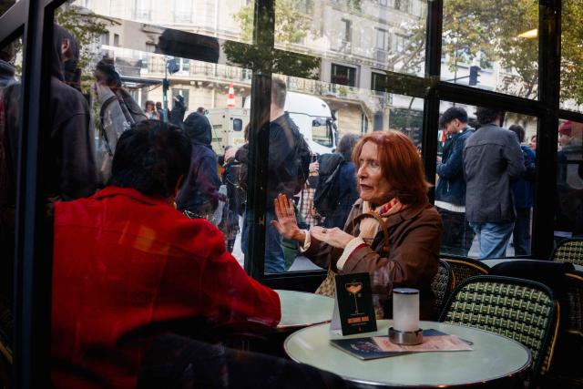 A woman sitting in a cafe reacts to the techno event of "Tekno Parade" in which the participants  against repression of free-party culture in France, in central Paris on October 18, 2025. (Photo by Dimitar DILKOFF / AFP)