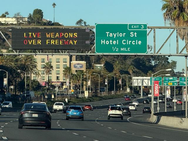 Freeway signs warn drivers on Interstate 8 approaching Interstate 5 of “Live Weapons Over Freeway” in San Diego, California on October 18, 2025. A major US freeway was set to close Saturday during a military live fire exercise that California officials said could endanger drivers. A 17-mile (27-kilometer) coastal stretch of the I-5 interstate between Los Angeles and San Diego will be affected while the Marine Corps fires live rounds over the route to mark its 250th anniversary in an event being attended by Vice President JD Vance. (Photo by Patrick Fallon / AFP)