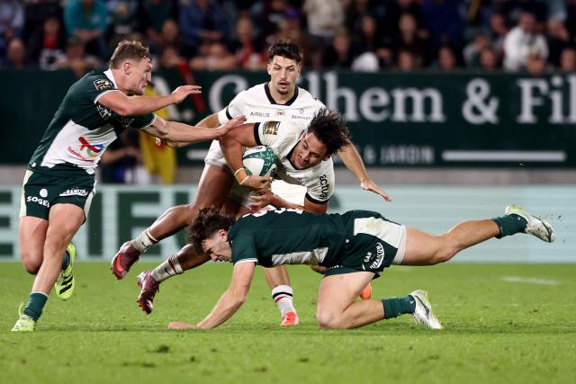 Toulouse's French centre Kalvin Gourgues (C) is tackled by Pau's French centre Fabien Brau-Boirie (bottom) during the French Top14 rugby union match between Section Paloise Bearn Pyrenees (Pau) and Stade Toulousain Rugby (Toulouse) at Stade du Hameau in Pau, south-western France on October 18, 2025. (Photo by ROMAIN PERROCHEAU / AFP)
