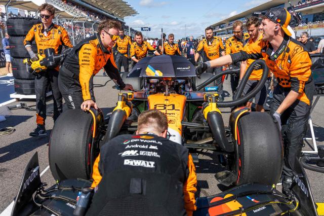 McLaren's Australian driver Oscar Piastri sits in his car with an umbrella over him as crew members tend to his car prior to the start of the United States Formula One Sprint at the Circuit of the Americas in Austin, Texas, on October 18, 2025. (Photo by Jim WATSON / AFP)