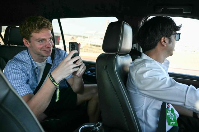 French swimmer Leon Marchand (L) rides in a vehicle as he gets a VIP tour of the track following the qualifying session for the United States Formula One Grand Prix at the Circuit of the Americas in Austin, Texas, on October 18, 2025. (Photo by Jim WATSON / AFP)