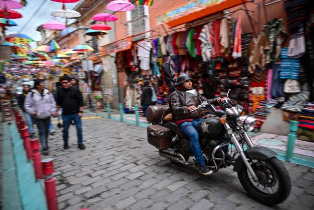 A man rides his motorbike through the popular Witches Market in La Paz on October 18, 2025. Bolivia chooses between two pro-business candidates in presidential elections on Sunday, ending two decades of socialist rule that have left the beleaguered South American nation deep in economic crisis. (Photo by MARTIN BERNETTI / AFP)