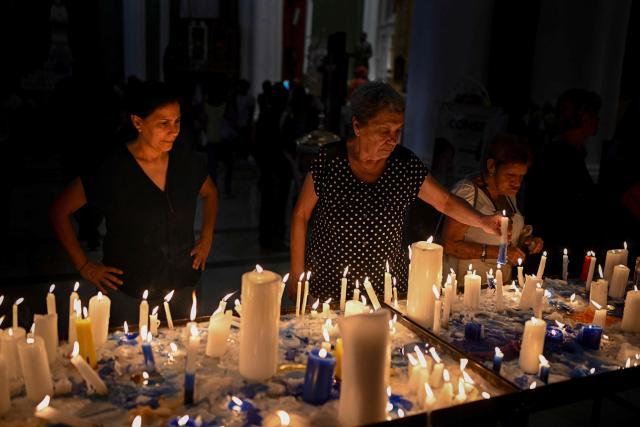 Catholic faithfuls light candles during a mass at the Nuestra Senora de la Candelaria church in Caracas on October 18, 2025. Pope Leo XIV is set to canonize Venezuela’s first saints, Dr. Jose Gregorio Hernandez and Sister Maria del Carmen Rendiles, during a ceremony in St. Peter's Square on October 19, 2025. (Photo by Federico PARRA / AFP)