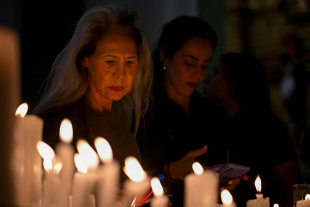 Catholic faithfuls light candles during a mass at the Nuestra Senora de la Candelaria church in Caracas on October 18, 2025. Pope Leo XIV is set to canonize Venezuela’s first saints, Dr. Jose Gregorio Hernandez and Sister Maria del Carmen Rendiles, during a ceremony in St. Peter's Square on October 19, 2025. (Photo by Federico PARRA / AFP)