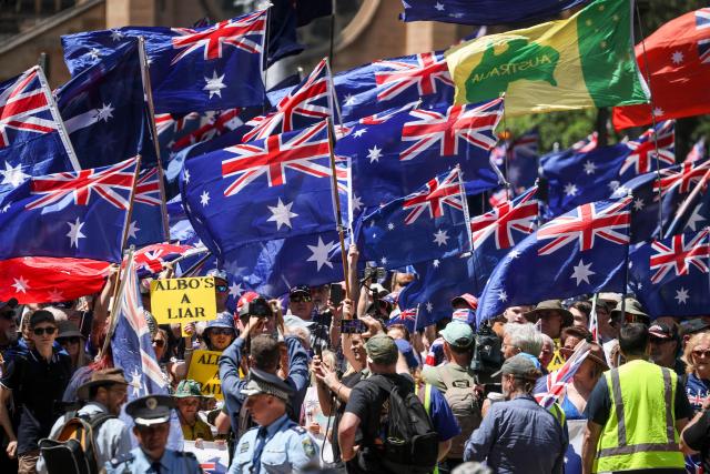 Protesters hold Australian national flags and banners as they participate in the March for Australia rally in central Sydney on October 19, 2025. (Photo by DAVID GRAY / AFP)