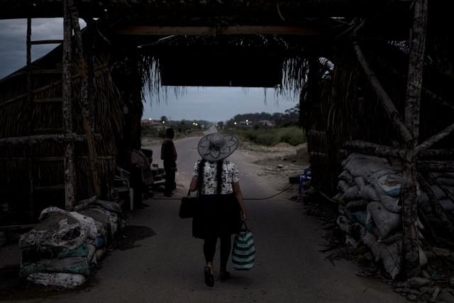 A woman crosses the gates of Lauca Ene, headquarters of the coca growers movement in Chapare province, Bolivia on October 18, 2025. Bolivia chooses between two pro-business candidates in presidential elections on Sunday, ending two decades of socialist rule that have left the beleaguered South American nation deep in economic crisis. (Photo by Ernesto BENAVIDES / AFP)