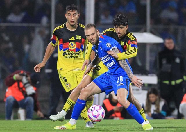 Cruz Azul's Argentine forward #29 Rodolfo Rotondi, America's Uruguayan defender #04 Sebastian Caceres and defender #05 Kevin Alvarez fight for the ball during the Liga MX Apertura football tournament match between Cruz Azul and america at the Olimpico Universitario Stadium in Mexico City on October 18, 2025. (Photo by Victor CRUZ / AFP)