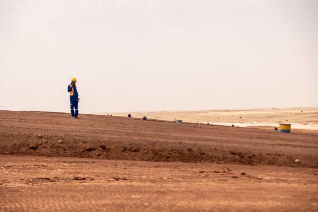(FILES) A mine worker walks on the residual dump at the Cominak mine near Arlit on March 8, 2023. Parisian investigating judges have referred nuclear giant Areva (now Orano) to trial for unintentional injury, suspected of being partly responsible for the 2010 kidnapping of five French citizens by Al-Qaeda near the Arlit uranium mine in Niger, AFP learned from sources close to the case on October 19, 2025. (Photo by OLYMPIA DE MAISMONT / AFP)