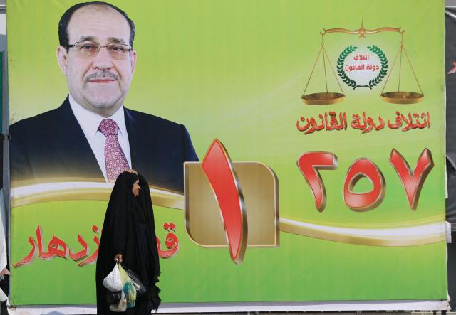 A woman walks past a electoral billboard bearing a portrait of former Iraqi prime minister Nuri al-Maliki in central Baghdad on October 19, 2025, ahead of Iraq's parliamentary elections on November 11. (Photo by AHMAD AL-RUBAYE / AFP)