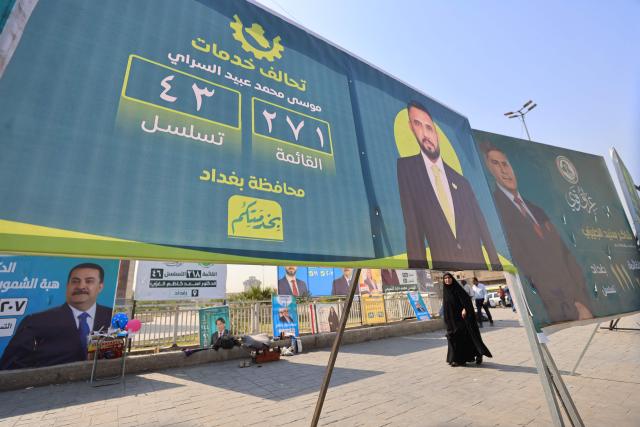 A woman walks past electoral billboards in central Baghdad on October 19, 2025, ahead of Iraq's parliamentary elections on November 11. (Photo by AHMAD AL-RUBAYE / AFP)