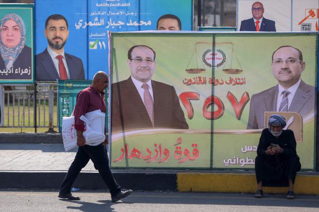 A Iraqi man walks past electoral billboards in central Baghdad on October 19, 2025, ahead of Iraq's parliamentary elections on November 11. (Photo by AHMAD AL-RUBAYE / AFP)